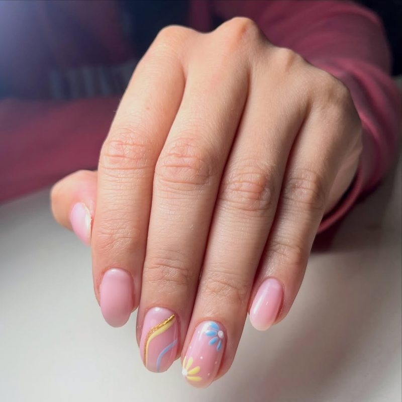 Uñas rosadas con flores y líneas doradas
